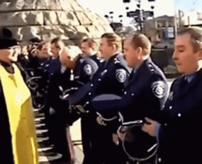 A Group Of Police Officers Are Standing In A Line Talking To Each Other . GIF