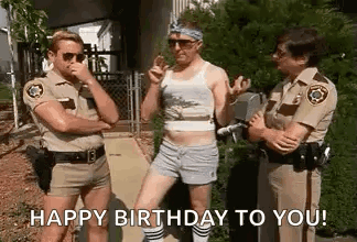 A Group Of Police Officers Are Standing Next To Each Other On A Sidewalk And One Of Them Is Wearing Shorts . GIF