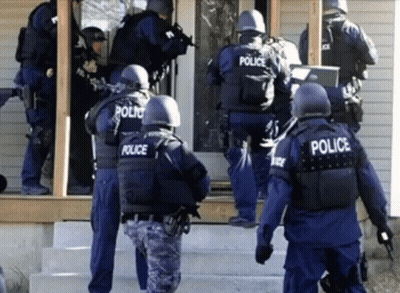 A Group Of Police Officers Are Standing Outside A House GIF