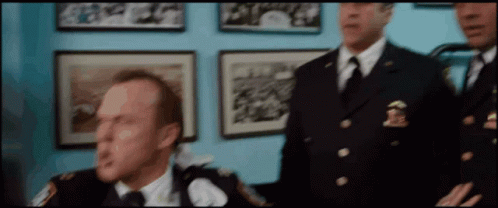 A Group Of Police Officers Standing In Front Of A Wall With Pictures On It GIF