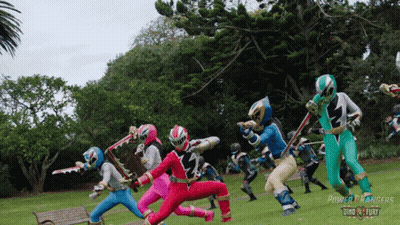 A Group Of Power Rangers In A Park GIF