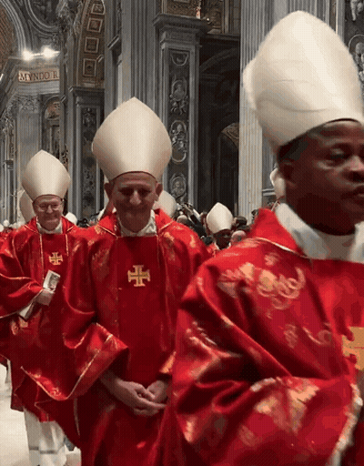 A Group Of Priests Are Walking In A Church And One Of Them Has A Cross On His Vest GIF