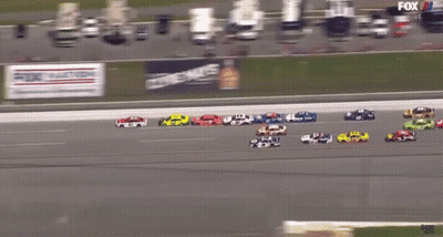 A Group Of Race Cars Are Racing On A Track With A Fox Live Advertisement Behind Them GIF