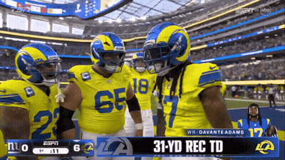 A Group Of Rams Football Players Are Standing On The Field GIF