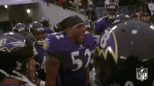A Group Of Ravens Football Players Are Huddled Together . GIF