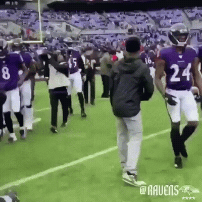 A Group Of Ravens Players Are Walking On The Field GIF