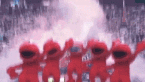 A Group Of Red Sesame Street Characters Are Standing In Front Of A Crowd GIF