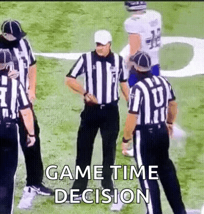 A Group Of Referees Are Standing On A Football Field Talking To A Player . GIF