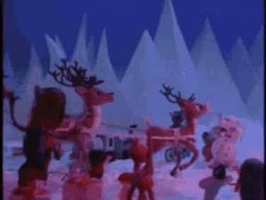 A Group Of Reindeer Are Standing In The Snow In A Christmas Scene . GIF