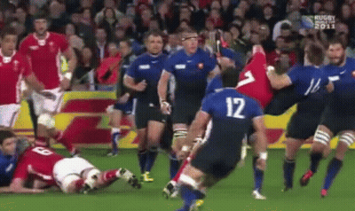 A Group Of Rugby Players Are Playing A Game On A Field . One Of The Players Has The Number 12 On His Jersey . GIF