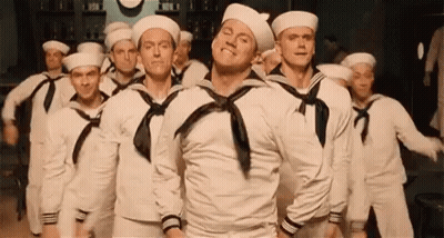 A Group Of Sailors Are Dancing In A Line In A Room . GIF