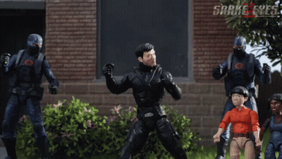 a group of snake eyes action figures are standing in front of a brick wall