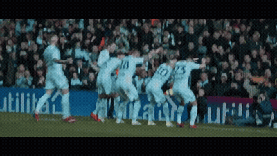 A Group Of Soccer Players Are Celebrating A Goal In Front Of A Sign That Says Utilita GIF