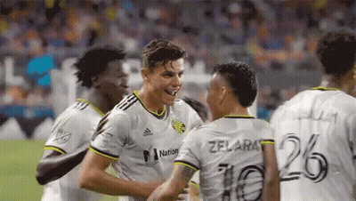 A Group Of Soccer Players Are Celebrating A Goal On A Field . GIF