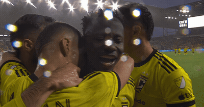 A Group Of Soccer Players Are Hugging Each Other In Front Of A Scoreboard That Says " Crew Goal " GIF