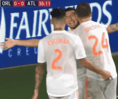 A Group Of Soccer Players Are Hugging Each Other In Front Of An Ad For Fairwinds GIF