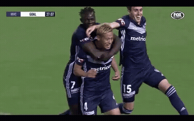 A Group Of Soccer Players Are Hugging Each Other On A Field . GIF