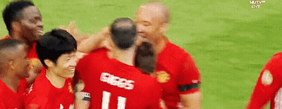 A Group Of Soccer Players Are Hugging Each Other On A Field With Mutv Live In The Background GIF