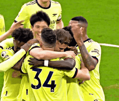 A Group Of Soccer Players Are Hugging Each Other On The Field . One Of The Players Has The Number 34 On His Shirt . GIF