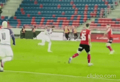 A Group Of Soccer Players Are Playing A Game On A Field With A Stadium In The Background . GIF