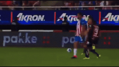 A Group Of Soccer Players Are Playing On A Field With An Ad For Akron Behind Them GIF