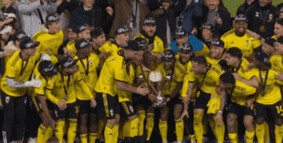 A Group Of Soccer Players Are Posing For A Picture With A Trophy That Says Champions On It GIF