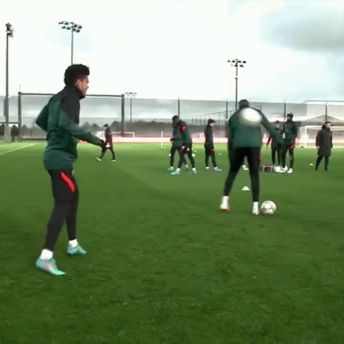 A Group Of Soccer Players Are Practicing On A Field With A Man Kicking A Soccer Ball GIF