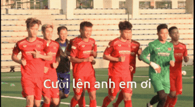 A Group Of Soccer Players Are Running On A Field With The Words Cuoi Len Anh Em Oi Written In White GIF
