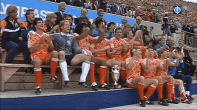 A Group Of Soccer Players Are Sitting On A Bench With A Trophy GIF