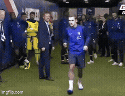 A Group Of Soccer Players Are Standing In A Locker Room And One Of Them Is Running . GIF