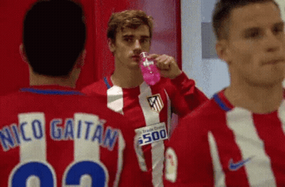 A Group Of Soccer Players Are Standing In A Locker Room Drinking Water From A Pink Bottle . GIF