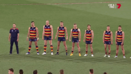 A Group Of Soccer Players Are Standing In A Row On A Field With A Live And Free Sign Above Them GIF