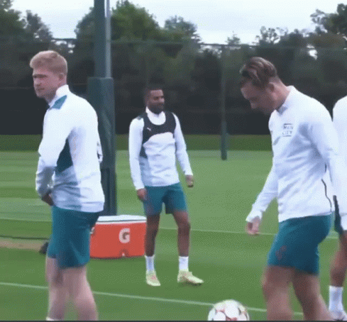 A Group Of Soccer Players Are Standing On A Field With An Orange Gatorade Cooler In The Background GIF