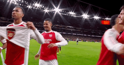 A Group Of Soccer Players Are Standing On A Field With Their Shirts Off . GIF