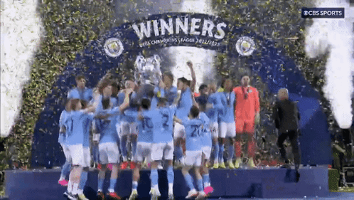 A Group Of Soccer Players Celebrate On A Stage With A Sign That Says " Winners " GIF