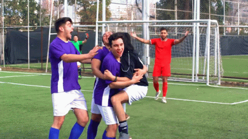 A Group Of Soccer Players In Purple And White Uniforms Are Celebrating A Goal GIF