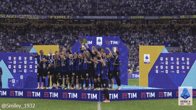 A Group Of Soccer Players Stand On A Podium Holding A Trophy In Front Of An Ad For Tim GIF