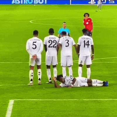a group of soccer players standing around a player laying on the field