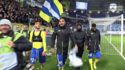 A Group Of Soccer Players Walking On A Field With A Fcsm Logo GIF