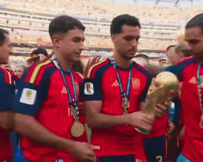 A Group Of Soccer Players With Medals Around Their Necks Are Holding A Trophy With The Number 7 On It GIF