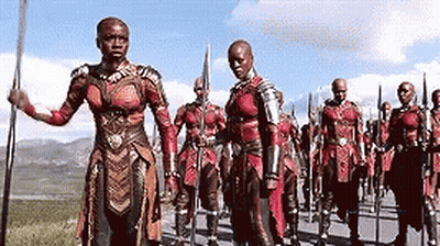 A Group Of Soldiers Are Marching Down A Road With Spears In Their Hands . GIF