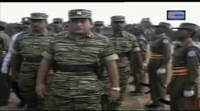 A Group Of Soldiers Are Standing In A Line With A Tv Screen Behind Them GIF