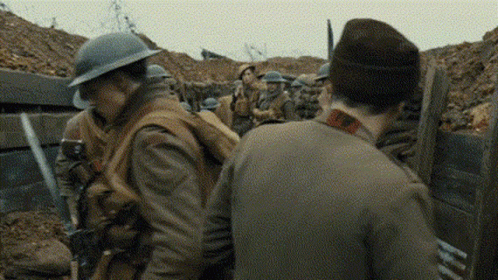 A Group Of Soldiers Are Standing In A Trench Talking To Each Other In A War Scene . GIF