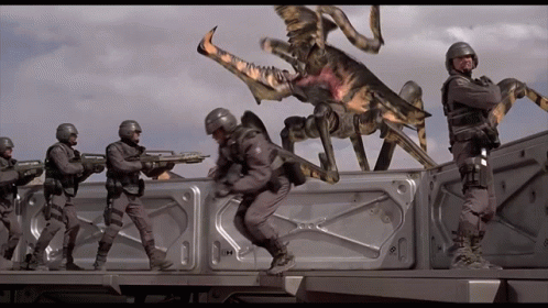A Group Of Soldiers Are Standing In Front Of A Bug That Has The Letter H On Its Back GIF