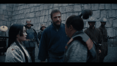 A Group Of Soldiers Are Standing In Front Of A Stone Wall And Talking To Each Other GIF