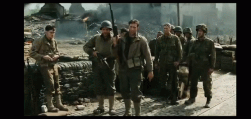 A Group Of Soldiers Are Walking Down A Cobblestone Street GIF