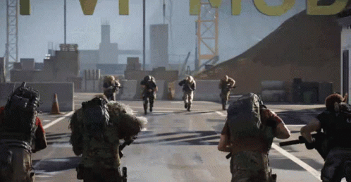 A Group Of Soldiers Are Walking Down A Street In Front Of A Large Yellow Sign That Says T.v.i. GIF