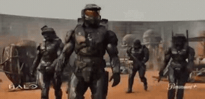 A Group Of Soldiers Are Walking In A Line In A Desert . GIF