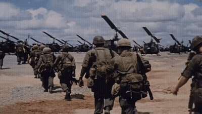 A Group Of Soldiers Are Walking In Front Of A Line Of Helicopters GIF