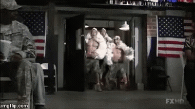 A Group Of Soldiers Are Walking Out Of A Building In Front Of American Flags . GIF
